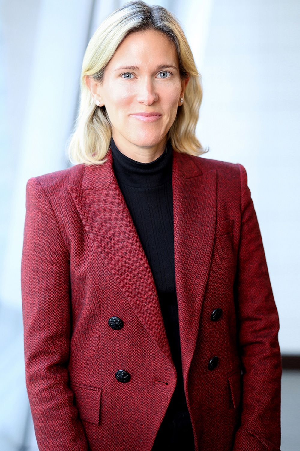 A professional woman sporting a red blazer and black turtleneck for headshots in NYC.